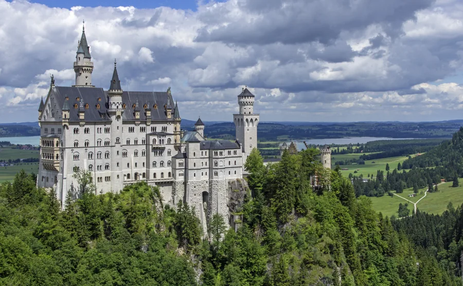 Un château blanc au-dessus de collines boisées