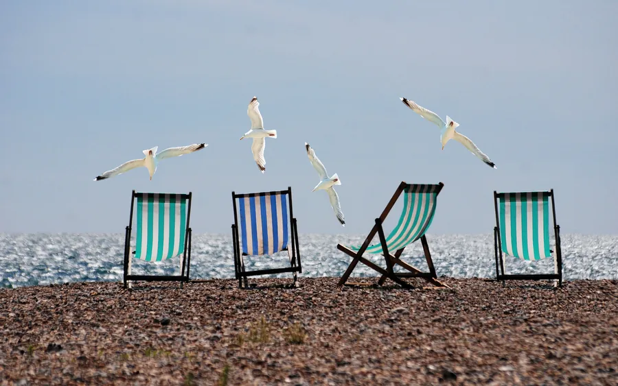 Gestreifte Liegestühle und Möwen am Kiesstrand
