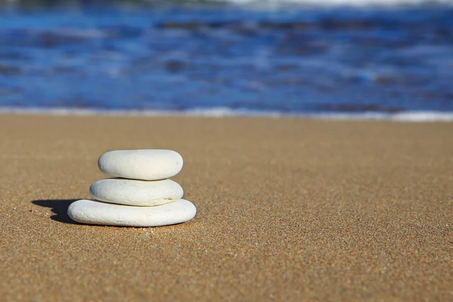 Three White Pebbles Stacked on Sand