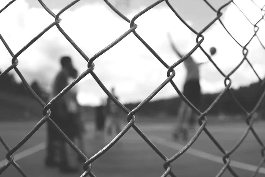 Players Seen Through a Chain-Link Fence
