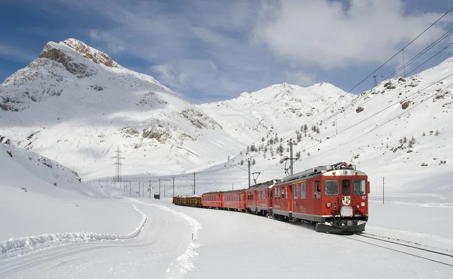 A Red Train Through Snowy Mountains