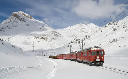 Un treno rosso tra montagne innevate