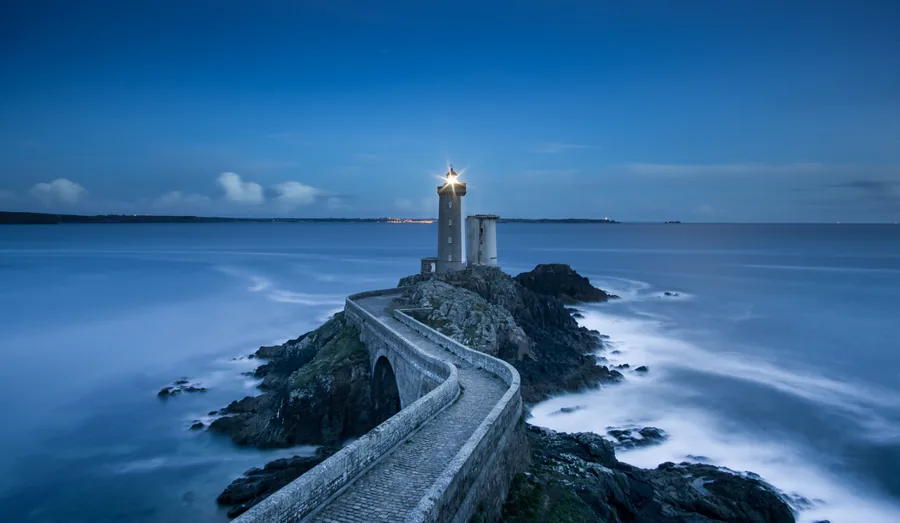 Lighthouse at the End of a Stone Bridge