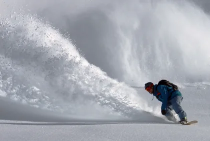 Uno snowboarder in curva nella neve fresca profonda